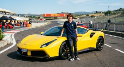 Junior driver smiling next to a yellow Ferrari