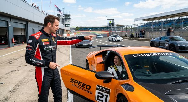 Driving instructor briefing a participant next to a Lamborghini