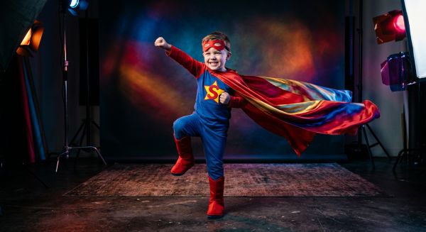 A child posing in a superhero costume for a themed photoshoot
