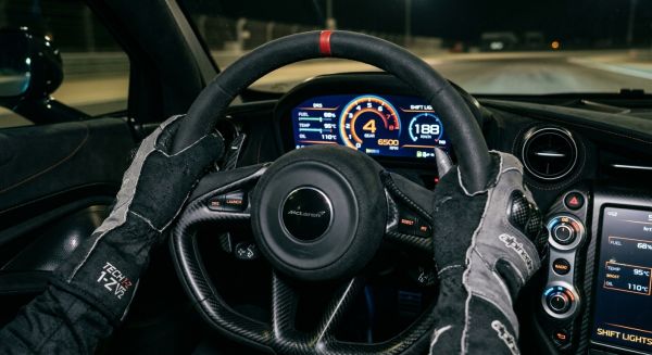 Driver holding the steering wheel of a supercar during a track day