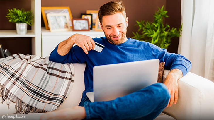Happy man shopping online with credit card on laptop at home – secure e-commerce, online payment, and internet banking