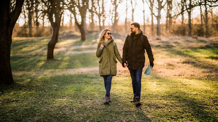 Couple enjoying romantic rural getaway walking hand-in-hand through peaceful countryside landscape