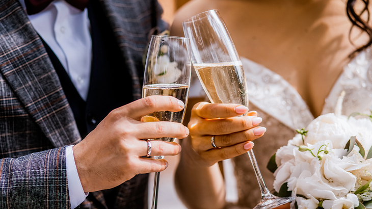 Close-up of bride and groom clinking champagne glasses celebrating wedding toast