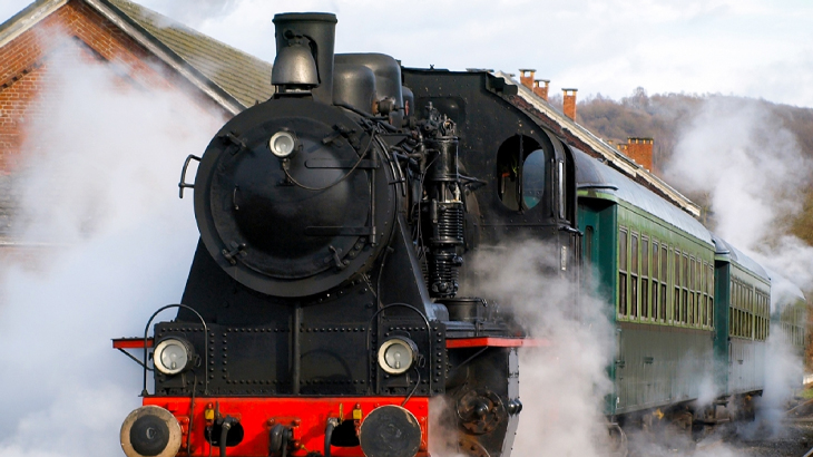 Steam train at platform surrounded by billowing steam, classic vintage train journey and scenic railway experience